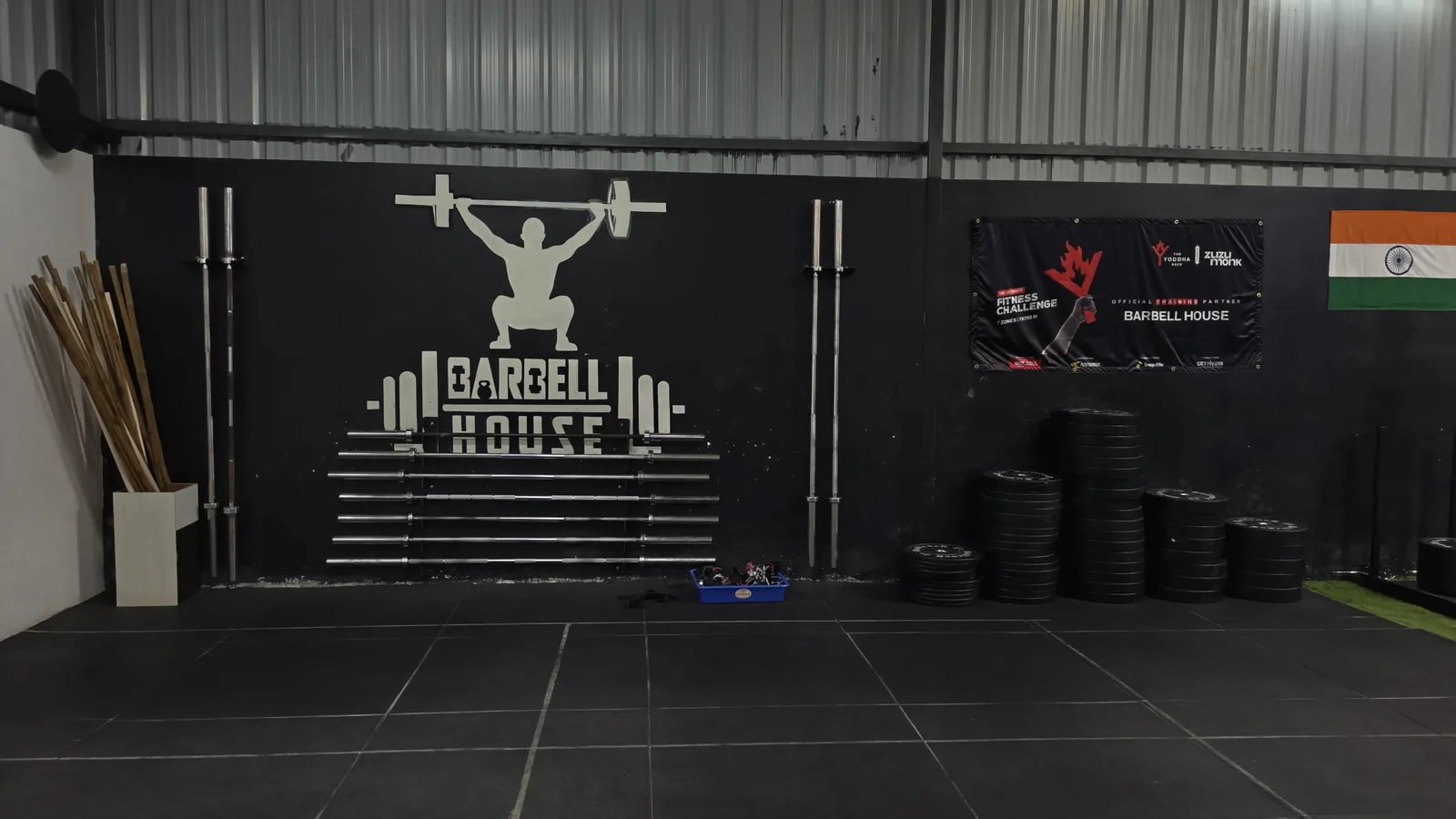 The Barbellhouse wordmark wall — bars stacked, plates ready